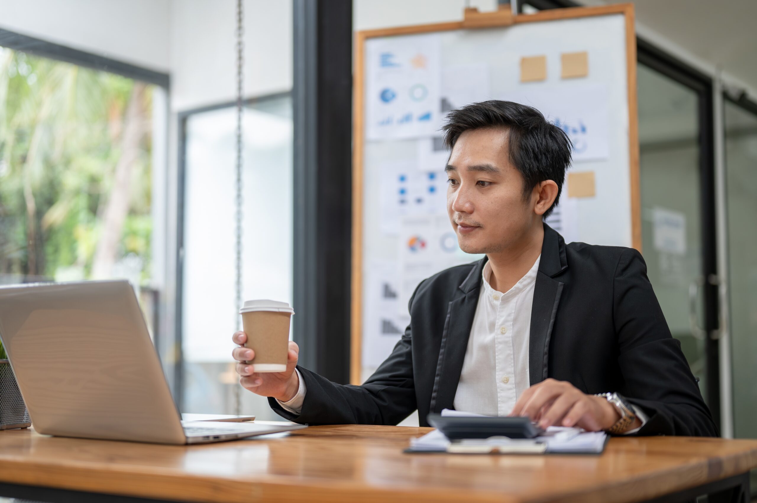 Singapore business owner reviewing payment data and analytics on a laptop in office